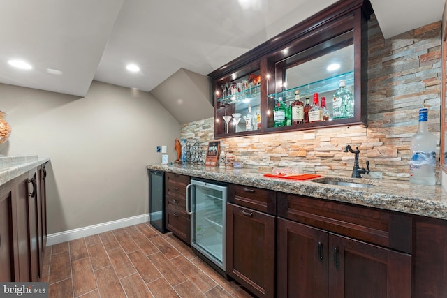 bar with wine cooler, sink, and light stone countertops