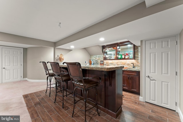 bar with tasteful backsplash, sink, and light stone counters