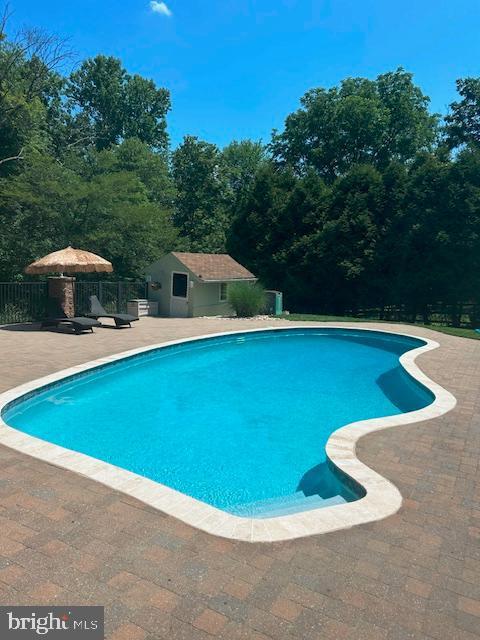 view of pool featuring an outbuilding and a patio area