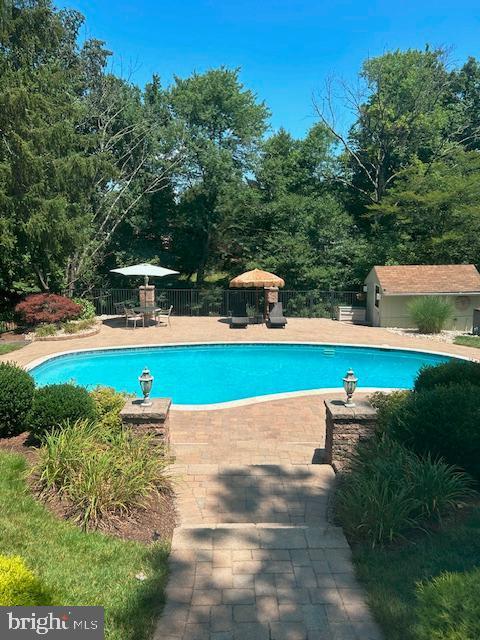 view of swimming pool featuring an outbuilding and a patio