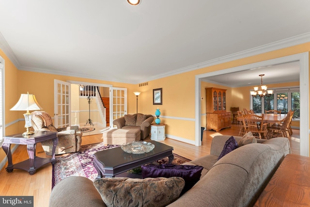 living room featuring ornamental molding, french doors, a chandelier, and light wood-type flooring