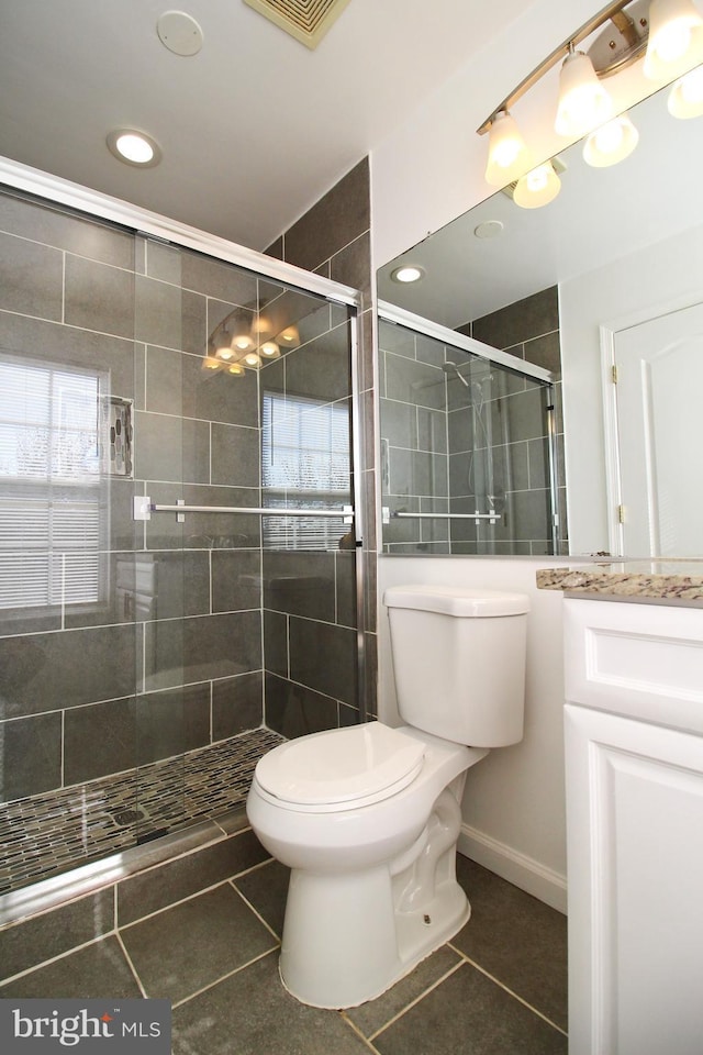 bathroom featuring vanity, a shower with door, tile patterned floors, and toilet