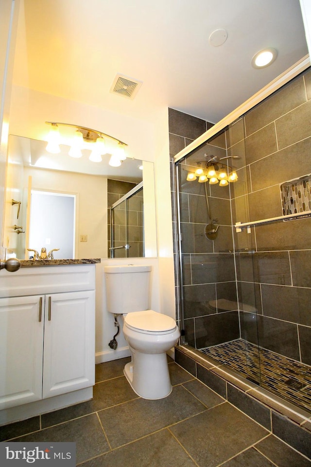 bathroom with tile patterned flooring, toilet, vanity, and walk in shower