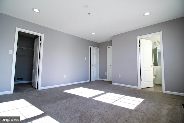 unfurnished bedroom with a spacious closet, carpet floors, and ensuite bathroom