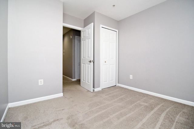 unfurnished bedroom featuring light colored carpet and a closet