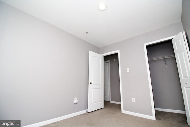 unfurnished bedroom with light carpet and a closet