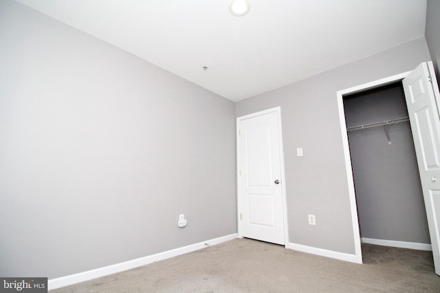 unfurnished bedroom with light colored carpet and a closet