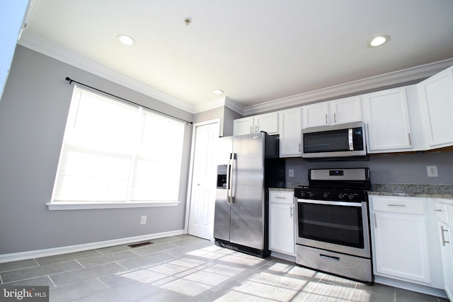 kitchen with appliances with stainless steel finishes, white cabinets, light tile patterned floors, light stone counters, and crown molding