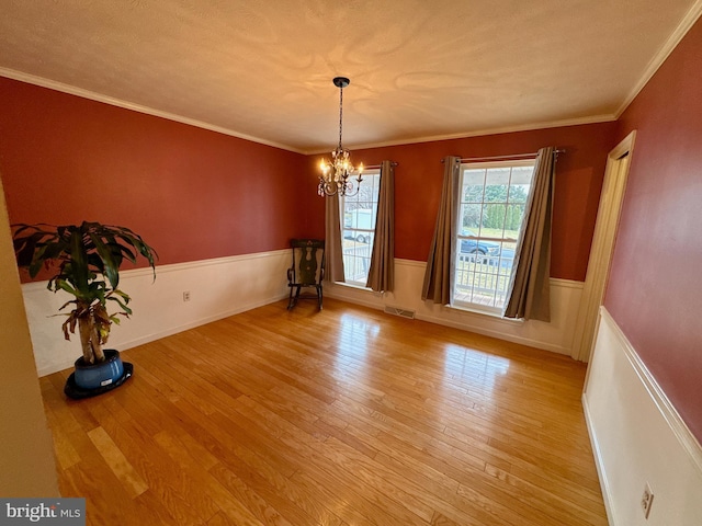 unfurnished dining area with an inviting chandelier, light hardwood / wood-style flooring, and ornamental molding