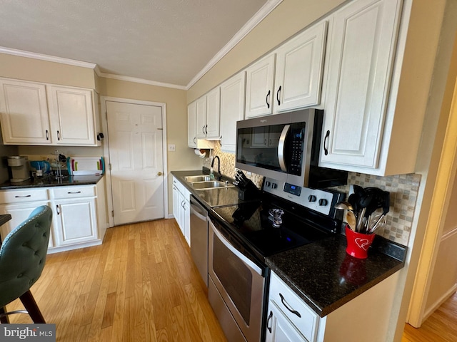 kitchen featuring sink, crown molding, appliances with stainless steel finishes, white cabinetry, and light wood-type flooring