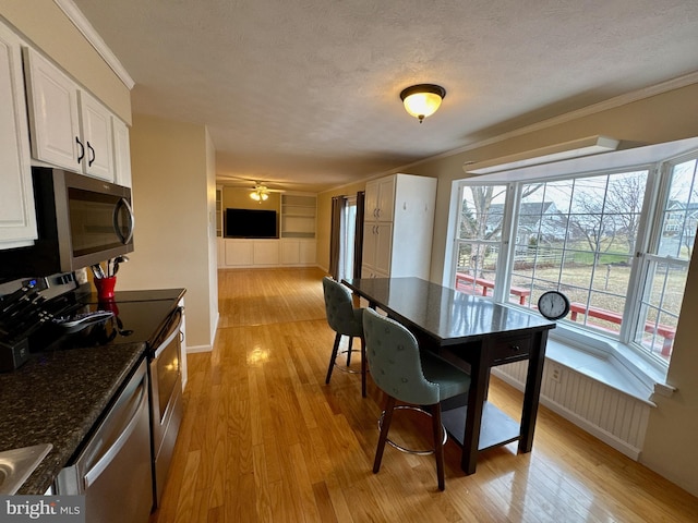 dining area with ornamental molding, light wood-type flooring, ceiling fan, and a textured ceiling