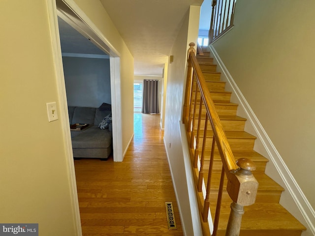 hall with ornamental molding and light hardwood / wood-style floors