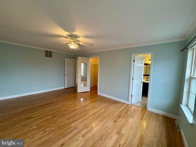 unfurnished bedroom featuring connected bathroom, a walk in closet, light wood-type flooring, ornamental molding, and ceiling fan