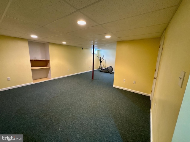 basement with a drop ceiling and dark carpet