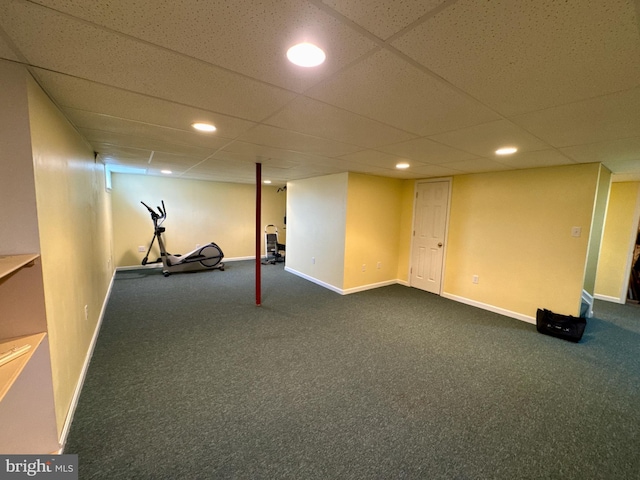 basement featuring a paneled ceiling and dark colored carpet