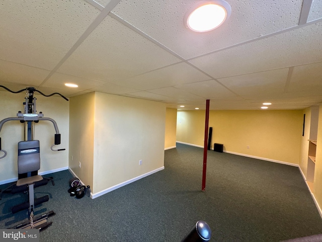 exercise area featuring a paneled ceiling and dark colored carpet