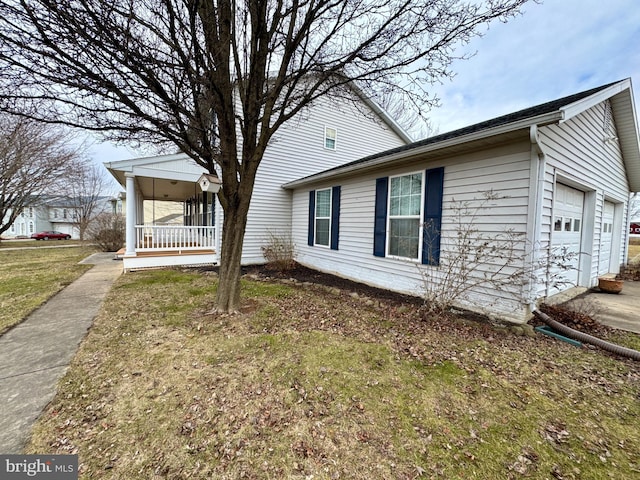 view of side of property with a garage, covered porch, and a lawn