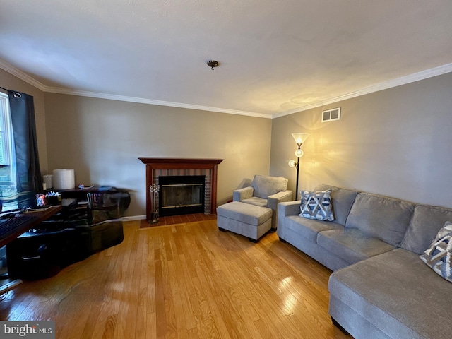 living room featuring hardwood / wood-style flooring, a tiled fireplace, and crown molding