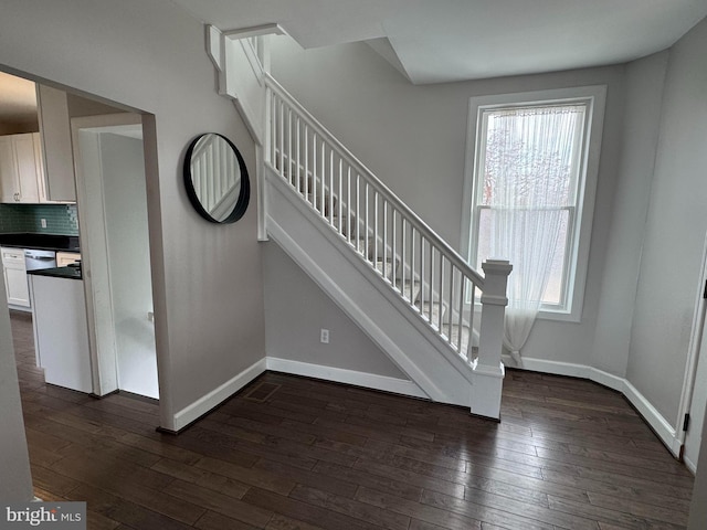 stairs with baseboards, wood finished floors, and plenty of natural light