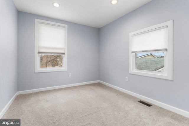 carpeted spare room featuring baseboards, a healthy amount of sunlight, and visible vents