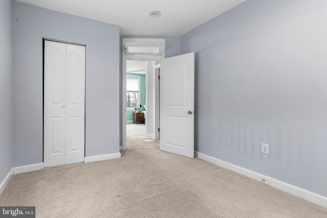 unfurnished bedroom featuring baseboards, a closet, and light carpet