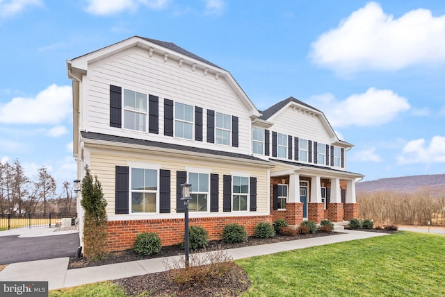 view of front of property with brick siding, a front yard, and covered porch