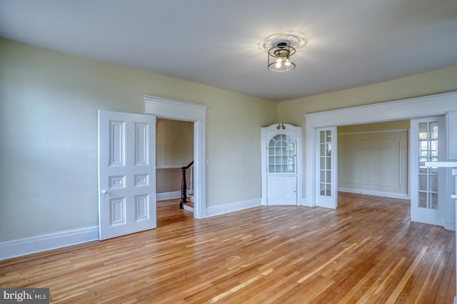 spare room featuring french doors and light wood-type flooring