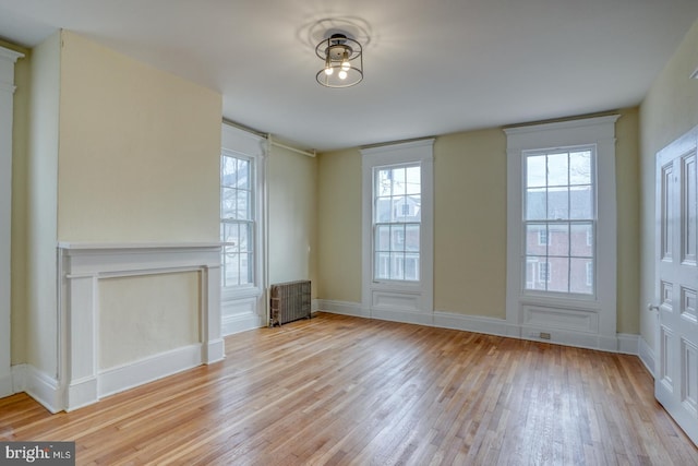 unfurnished living room featuring radiator and light hardwood / wood-style floors