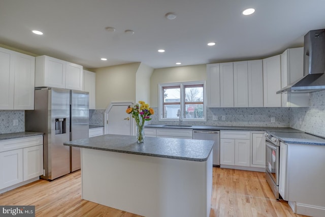 kitchen featuring a kitchen island, appliances with stainless steel finishes, sink, white cabinets, and wall chimney exhaust hood