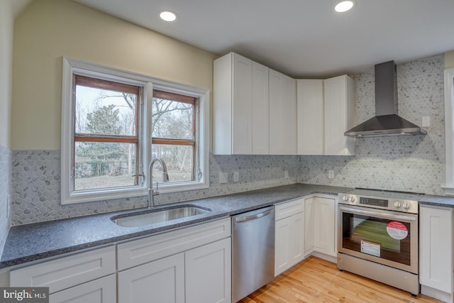 kitchen featuring white cabinetry, sink, wall chimney exhaust hood, and appliances with stainless steel finishes