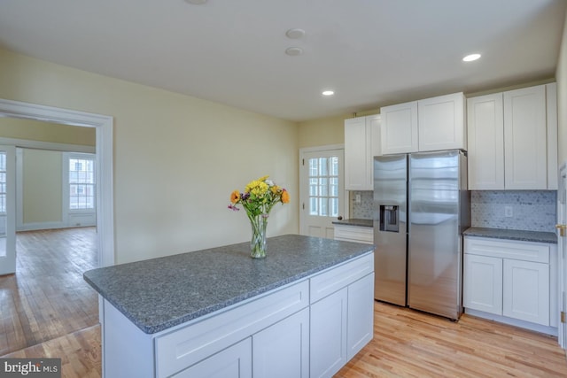 kitchen featuring stainless steel fridge, white cabinetry, a healthy amount of sunlight, a kitchen island, and light wood-type flooring