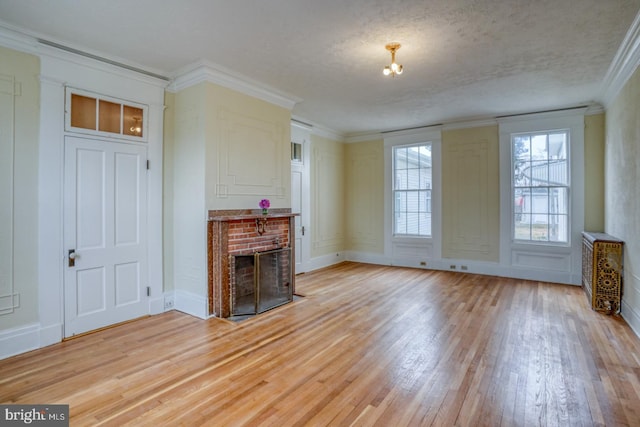 unfurnished living room featuring crown molding, a textured ceiling, a fireplace, and light hardwood / wood-style floors