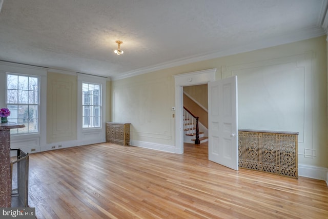 unfurnished living room with ornamental molding, a textured ceiling, and light hardwood / wood-style flooring