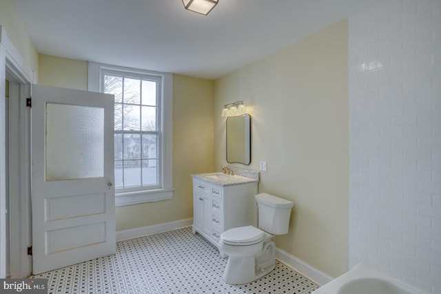 bathroom featuring vanity, a washtub, and toilet