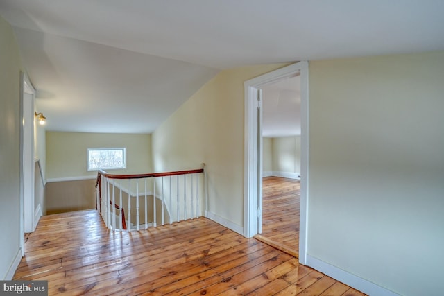 hall featuring lofted ceiling and light hardwood / wood-style flooring