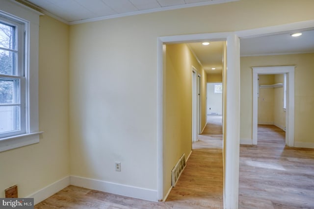 hallway with crown molding and light wood-type flooring