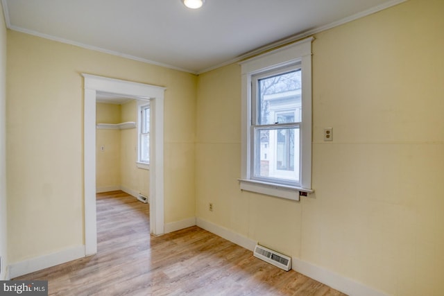 empty room with ornamental molding, light hardwood / wood-style floors, and a wealth of natural light