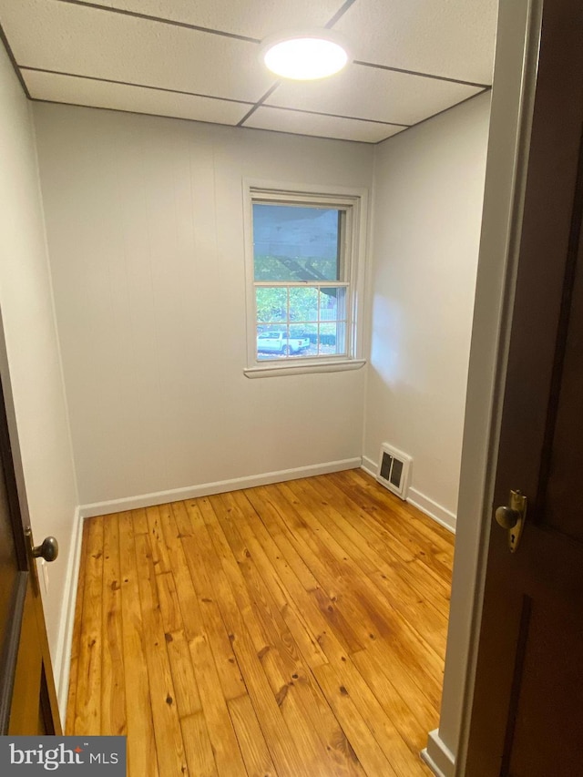 empty room featuring a drop ceiling and light hardwood / wood-style floors