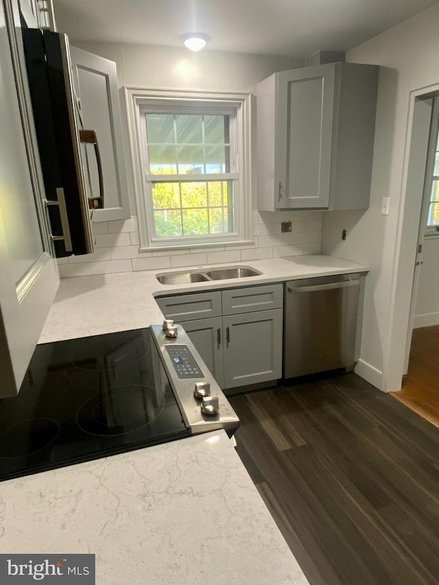 kitchen with tasteful backsplash, appliances with stainless steel finishes, dark hardwood / wood-style flooring, and sink