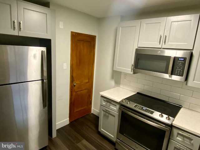 kitchen featuring stainless steel appliances, white cabinetry, dark hardwood / wood-style floors, and decorative backsplash