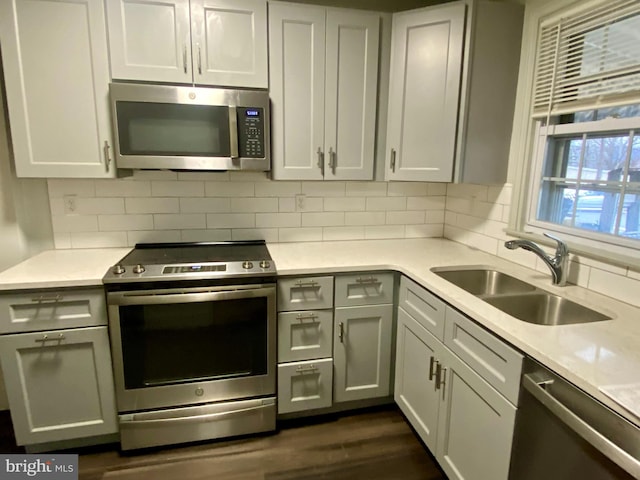 kitchen featuring light stone countertops, appliances with stainless steel finishes, sink, and backsplash