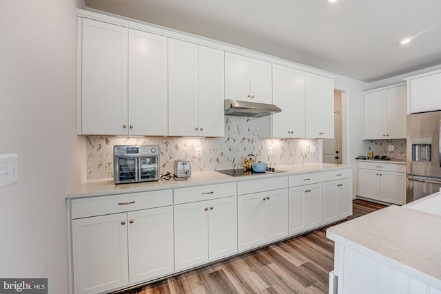 kitchen with white cabinetry, backsplash, black electric stovetop, stainless steel refrigerator with ice dispenser, and light wood-type flooring