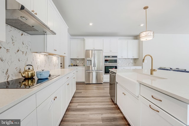 kitchen with appliances with stainless steel finishes, decorative light fixtures, white cabinetry, sink, and decorative backsplash