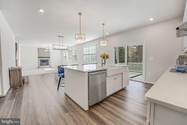 kitchen featuring white cabinetry, hanging light fixtures, stainless steel dishwasher, a kitchen island with sink, and hardwood / wood-style floors