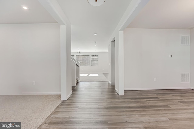 hallway with an inviting chandelier and light hardwood / wood-style flooring