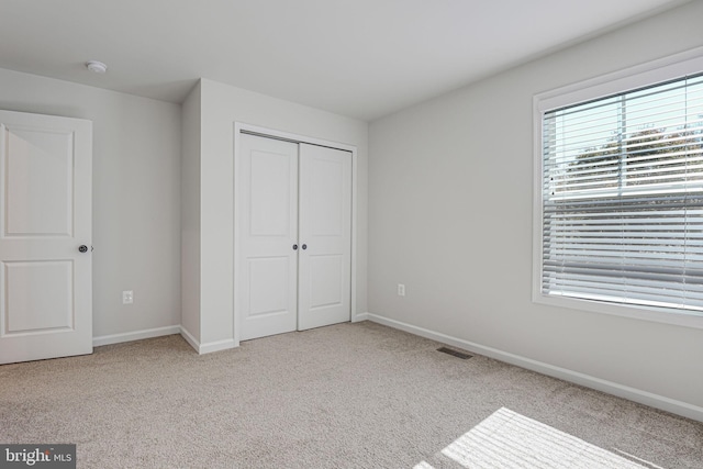 unfurnished bedroom with a closet and light carpet