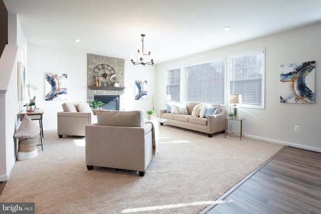 living room featuring a stone fireplace, a notable chandelier, and light hardwood / wood-style flooring