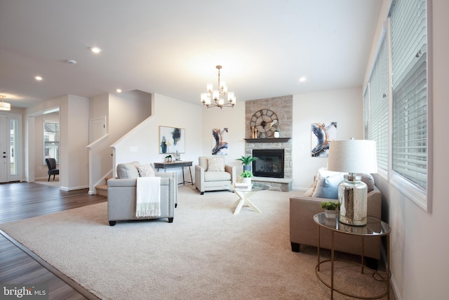 living room featuring a stone fireplace, plenty of natural light, a chandelier, and hardwood / wood-style flooring