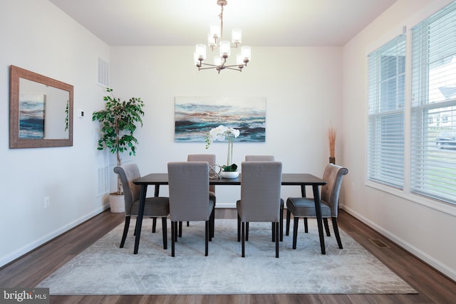 dining space with dark hardwood / wood-style flooring and an inviting chandelier