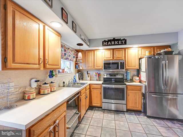 kitchen with pendant lighting, appliances with stainless steel finishes, sink, and tasteful backsplash